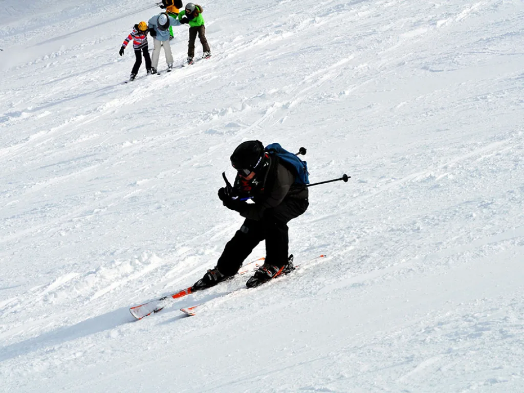 Skifahrer in tiefer Hocke auf der sonnigen Piste.